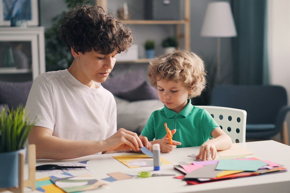 Adult and child working on a craft project together at a table