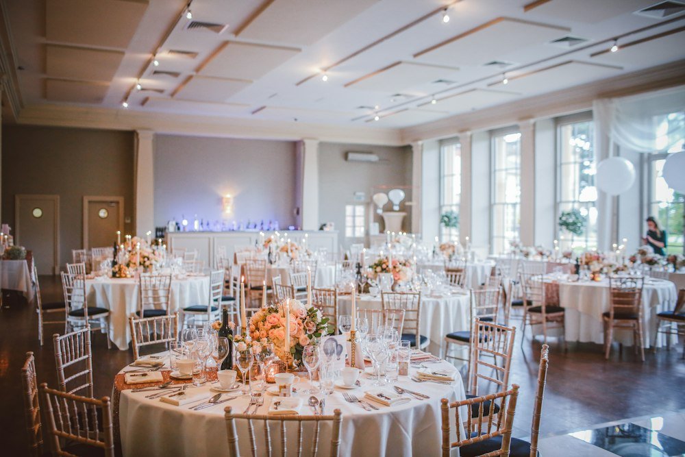 Event venue with round tables and floral centerpieces set for a reception