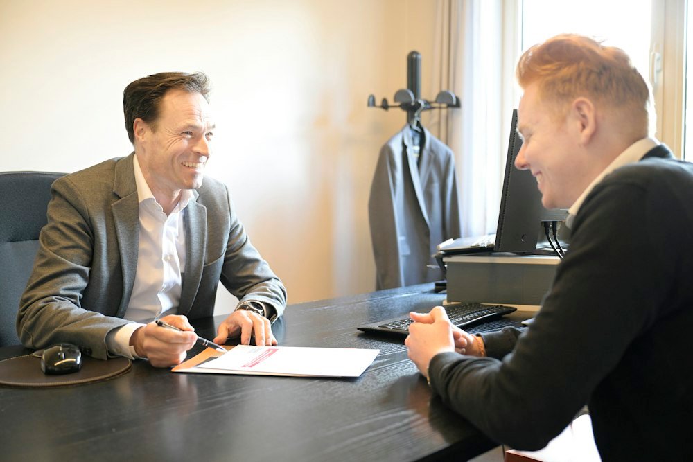 Two professionals smiling while reviewing documents at an office desk